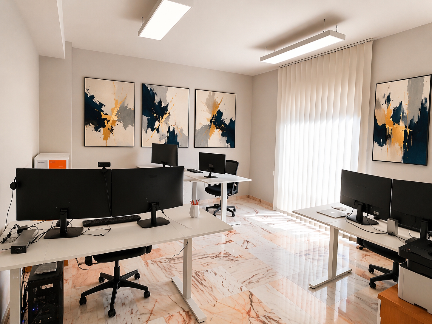 Sala operativa del coworking Reengineering Nexus a Cosenza con scrivanie elettriche regolabili, setup multi-monitor, pavimento in marmo rosa del Portogallo e illuminazione LED professionale