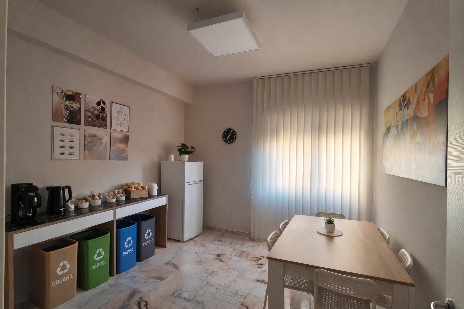 Sala ristoro del coworking Reengineering Nexus a Cosenza: area coffee break con macchina del caffè e bollitore, frigorifero, tavolo pranzo e luce naturale